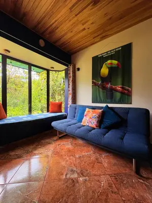 a living room with a blue couch and some windows at TucanTico Lodge - Monteverde in Monteverde Costa Rica