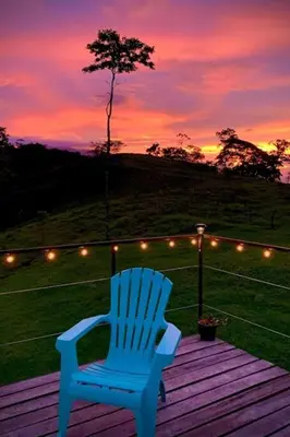 a blue chair sitting on a deck with a sunset at Alto Luciérnaga in Guayacán