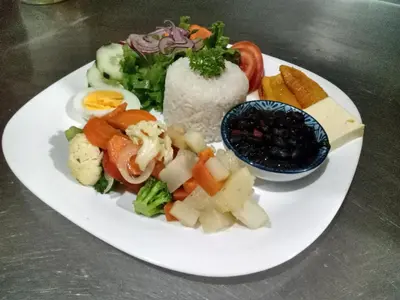 a plate of food with vegetables and rice on a table at Casita Lidia Bijagua in Bijagua