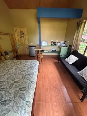 a room with a bed and a table and a couch at OXÍGENO Río Celeste in Bijagua