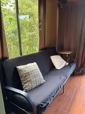 a black couch sitting in front of a window at OXÍGENO Río Celeste in Bijagua