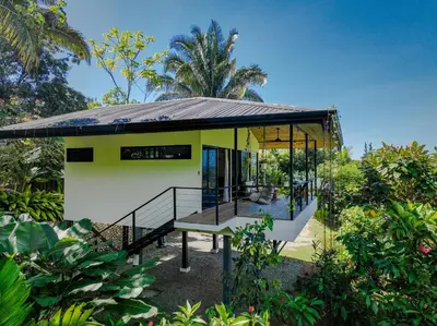 a small yellow house with a porch in a garden at Private Casita Jungle Treehouse Ocean View in Uvita