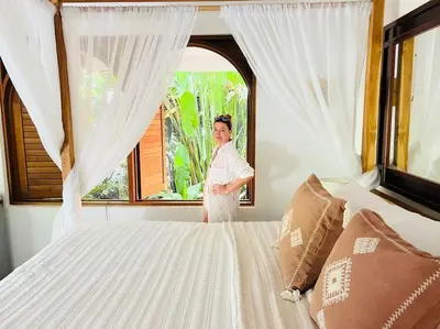 a woman standing next to a bed in a bedroom at Villas Almendros in Santa Teresa Beach