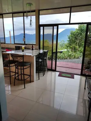 a kitchen with a table and chairs and a large window at Villas Altos del Arenal in Fortuna