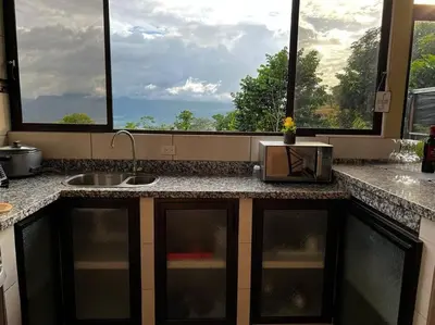 a kitchen with a counter with a sink and two windows at Villas Altos del Arenal in Fortuna