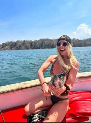 a woman sitting on a boat holding a fish at La Perla Negra Eco Pirate Resort in Puntarenas