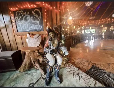 a woman is sitting on a table in a room at La Perla Negra Eco Pirate Resort in Puntarenas