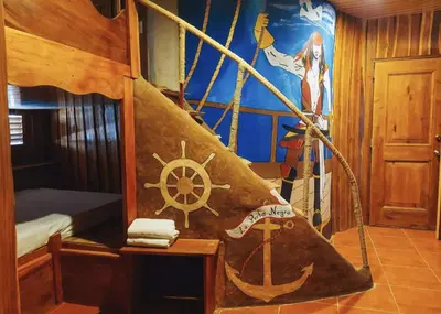 a room with a bed and a painting of a ship at La Perla Negra Eco Pirate Resort in Puntarenas