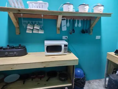 a microwave on a shelf with pots and pans at Residencia las brisas Griegas in Quepos