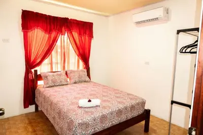 a bedroom with a bed with red curtains and a window at Residencia las brisas Griegas in Quepos