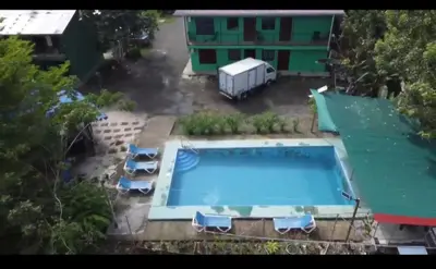a swimming pool with chairs and a building at Residencia las brisas Griegas in Quepos