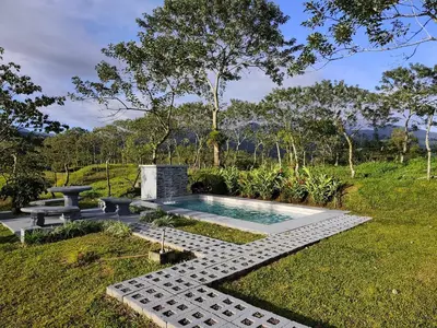 a swimming pool in the middle of a garden with a bench at Casa Esperanza in Río Cuarto