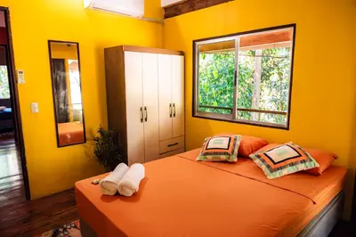 a bedroom with yellow walls and a bed with two pillows at Miles Away in Cóbano