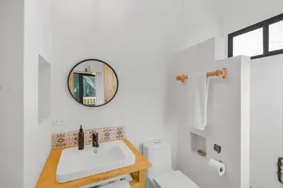 a bathroom with a sink and a toilet and a mirror at Casas Teresa Mar in Santa Teresa Beach