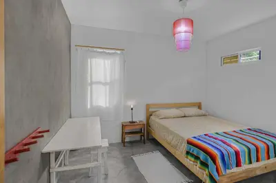 a bedroom with a bed and a table and a window at Casas Teresa Mar in Santa Teresa Beach