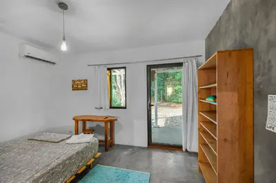 a bedroom with a bed and a table and a window at Casas Teresa Mar in Santa Teresa Beach
