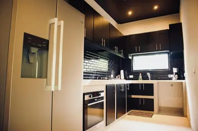 a kitchen with black cabinets and a flat screen tv at Jungle Home with King Beds -5 Minutes from the Beach in Uvita