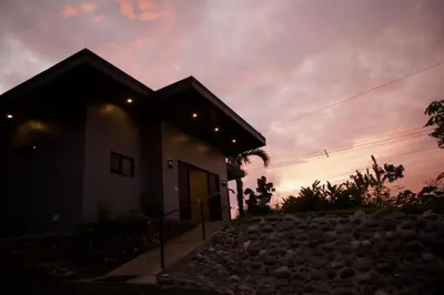 a house with a sunset in the background at Jungle Home with King Beds -5 Minutes from the Beach in Uvita