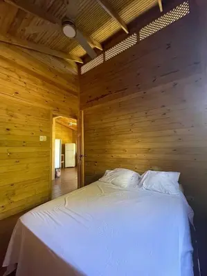 a bedroom with a white bed in a wooden wall at Villa Cola de Ballena Uvita in Uvita
