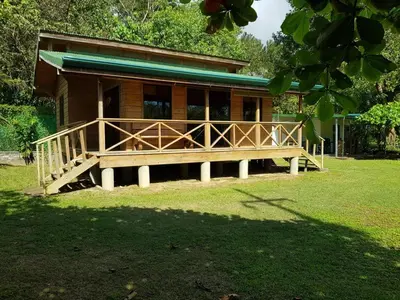 a house with a large wooden deck in the grass at Villa Cola de Ballena Uvita in Uvita