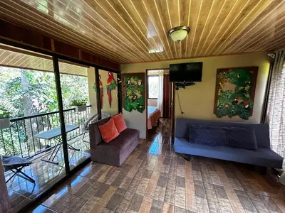 a room with a balcony with a couch and a tv at Eco Villas Tambor Tucanes in Tambor