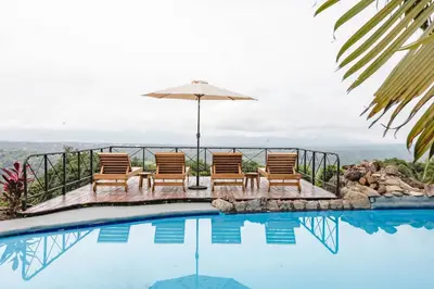 a group of chairs and an umbrella next to a swimming pool at Buen Camino Hotel, San Mateo in San Mateo