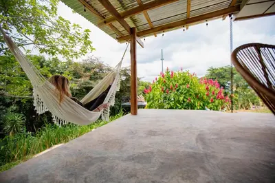 a woman sitting in a hammock on a porch at Buen Camino Hotel, San Mateo in San Mateo
