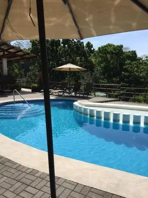 a large swimming pool with an umbrella and chairs at Herradura Home 2 in Herradura