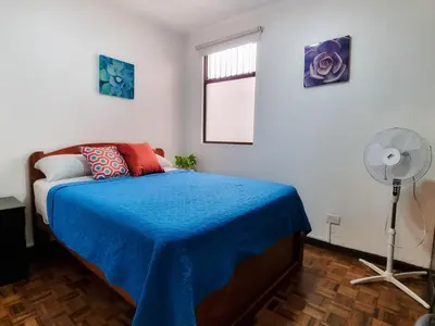 a bedroom with a bed with a blue blanket and a fan at 714 Studios in San José