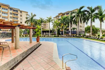 a swimming pool with palm trees and buildings at Costa Linda 2-28 in Jacó