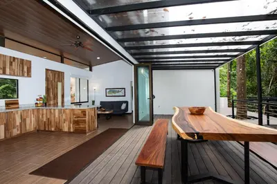 a kitchen and living room with a wooden table at Casa Henaway - Portasol Vacation in Savegre