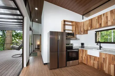 a kitchen with a stainless steel refrigerator and a deck at Casa Henaway - Portasol Vacation in Savegre