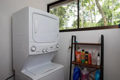 a white washer and dryer in a bathroom with a window at Casa Henaway - Portasol Vacation in Savegre