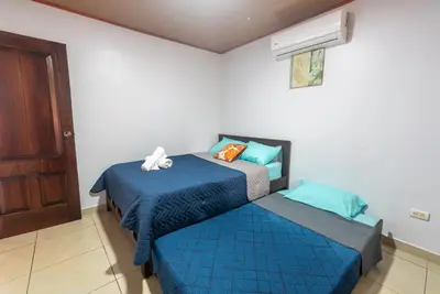a bedroom with two beds with blue sheets and a window at Villa JADE, La Fortuna Downtown in Fortuna
