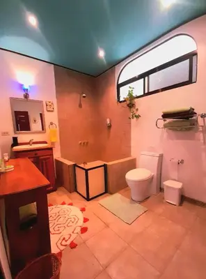 a bathroom with a toilet and a sink and a window at Nirvana Apartament Hostal in Alajuela City