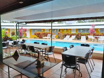 a patio with tables and chairs and a swimming pool at Hotel Puerta del Sol - San Jose Airport in San José