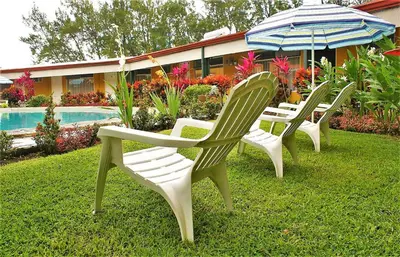 four lawn chairs and an umbrella next to a pool at Hotel Puerta del Sol - San Jose Airport in San José
