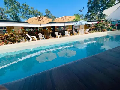 a swimming pool with chairs and umbrellas at Hotel Puerta del Sol - San Jose Airport in San José
