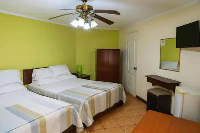 a bedroom with two beds and a ceiling fan at Hotel Puerta del Sol - San Jose Airport in San José