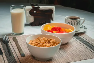 a table with two bowls of cereal and a glass of milk at Hotel El Cocobolo Food&Rest Room 2 B&B WiFi AC Pkg Free Swimmingpool in Ahogados