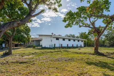 a white building in a field with trees at Hotel El Cocobolo Food&Rest Room 2 B&B WiFi AC Pkg Free Swimmingpool in Ahogados
