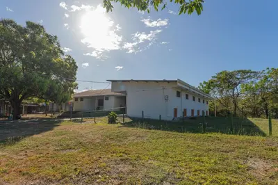 a white building in a field next to a yard at Hotel El Cocobolo Food&Rest Room 2 B&B WiFi AC Pkg Free Swimmingpool in Ahogados