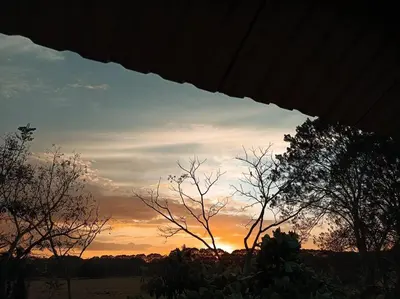 a sunset in the sky with trees in the foreground at Manantial de Vida in Bejuco