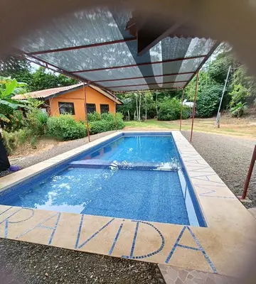 a swimming pool with awning in front of a house at Manantial de Vida in Bejuco