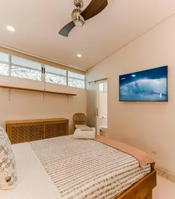 a bedroom with a large bed and a flat screen tv at BoHo Home in Gated Eco Residence marAmar - Top location in Santa Teresa Beach