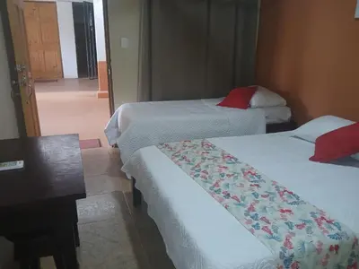 a hotel room with two beds and a table at Hotel El Cocobolo Food&Rest Room 4 B&B WiFi AC Pkg Free Swimmingpool in Liberia