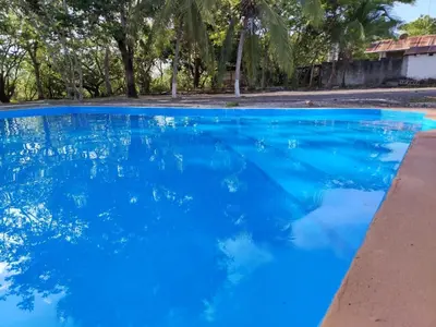 a pool of blue water with trees in the background at Hotel El Cocobolo Food&Rest Room 4 B&B WiFi AC Pkg Free Swimmingpool in Liberia