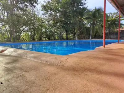 a large blue swimming pool with trees in the background at Hotel El Cocobolo Food&Rest Room 4 B&B WiFi AC Pkg Free Swimmingpool in Liberia