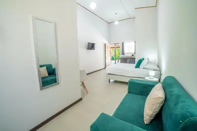 a living room with a green couch and a bed at Natüra Hotel Monteverde in Monteverde Costa Rica