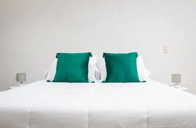 a white bed with two green pillows on it at Natüra Hotel Monteverde in Monteverde Costa Rica